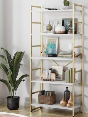 Modern gold bookshelf with five white shelves, displaying books, decor items, and plants, placed in a stylish living room with natural light.