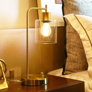 Gold industrial table lamp featuring a clear glass shade, modern design, and two USB ports for convenient device charging, paired with a sleek gold base